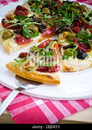 Pizza mit allerlei Tomaten, Aubergine, Oliven, Mozzarella und Rucola - Stockfoto