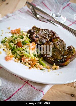 Zwei Lammkoteletts mit Couscous mit Gemüse auf weißem Teller - Stockfoto