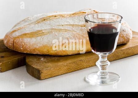 Glas Rotwein mit knusprig rustikalem Weißbrot auf Holzbrett - Stockfoto