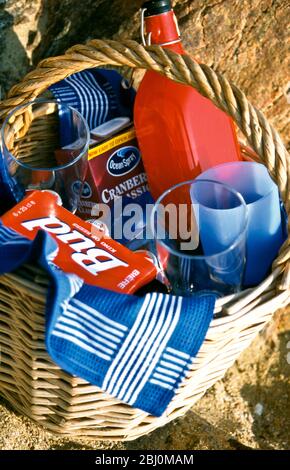 Picknickkorb am Sandstrand mit Getränken und Gläsern - Stockfoto