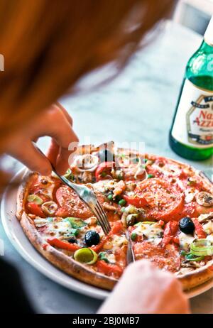 Pizza essen im Restaurant Pizza Express mit einer Flasche Nastro Azzuro Bier. - Stockfoto