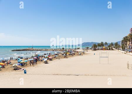 Strand von Torrenostra, Spanien. Juli 2019. Schöner Strandort an der mittelmeerküste in der Nähe von Valencia. Sonniger Sommertag, blauer Himmel und überfüllter Strand. Stockfoto