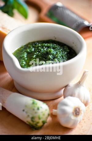 Herstellung von hausgemachter Pesto in Pestel und Mörser mit Zutaten rund um - Stockfoto