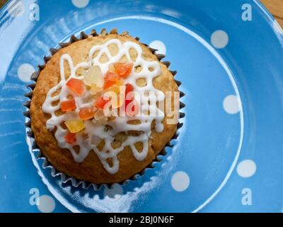 Muffin mit Squiggly Eisbildung und kandierten Schale auf gepunkteten blauen Teller verziert - Stockfoto