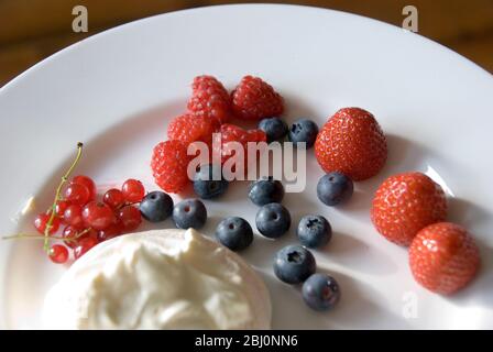 Leichte Sommerdessert aus frischen Beeren mit Schlagsahne gemischt mit Joghurt - Stockfoto