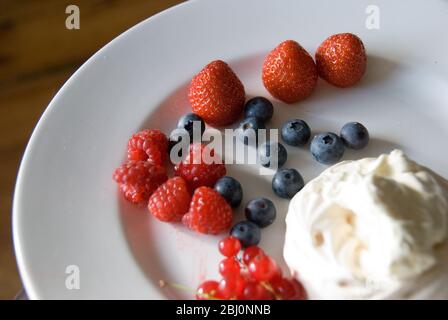 Leichte Sommerdessert aus frischen Beeren mit Schlagsahne gemischt mit Joghurt - Stockfoto