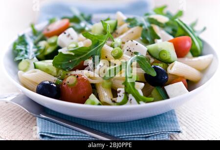 Leichter, gesunder Salat aus Rucola und Mozzarella-Würfeln mit Penne-Nudelformen, in leichter Vinaigrette eingeprägt. Kurze Schärfentiefe - Stockfoto