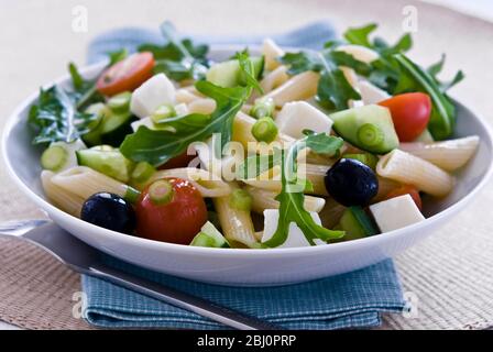 Leichter, gesunder Salat aus Rucola und Mozzarella-Würfeln mit Penne-Nudelformen, in leichter Vinaigrette eingeprägt. Schärfere Version - Stockfoto