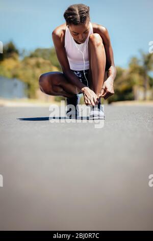 Fitness Frau, die ihr Schuhwulder auf der Straße im Freien festbindet. Frau am Morgen laufen Befestigung ihrer Schnürsenkel. Stockfoto