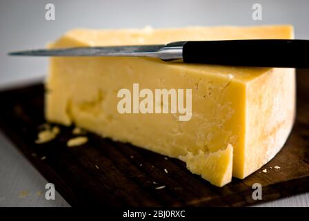 Keil Cheddar-Käse, auf Holzkäseplatte geschnitten - Stockfoto