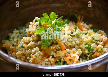 Gesunde Mittagszeit Salat aus Burghulweizen mit geriebener Karotte, Zitronensaft, Olivenöl, gehackte Gurke und Petersilie. - Stockfoto