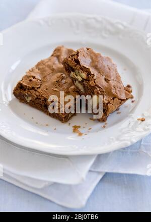 Schokoladennuss Brownies auf weißem Teller mit weißer Organza Serviette - Stockfoto