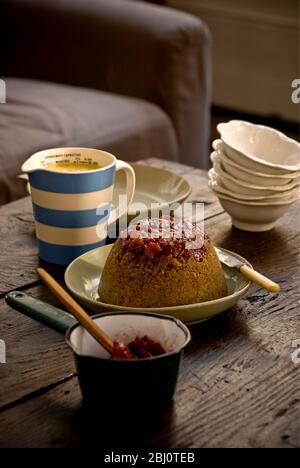 Traditioneller gedämpfter Schwammpudding mit Walniten und Rhabarber-Kompott und Pudding, serviert in ungezwungener Atmosphäre - Stockfoto