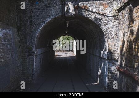 Dunkler Fußgängertunnel unter der Eisenbahn nahe dem Bahnhof Barnes im Südwesten Londons; ein Licht am Ende eines Tunnelkonzepts Stockfoto