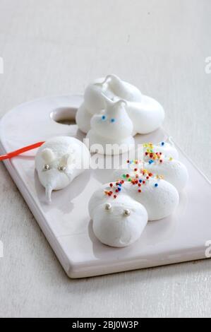 Phantasievolle Kreaturen, darunter Schnecke und Schlange, und eine kleine Maus oder Spitzmaus aus Meringue auf weißem Porzellan - Stockfoto