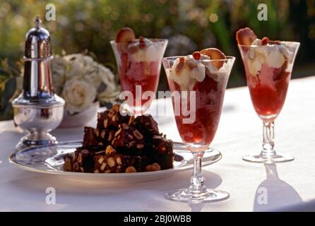 Erdbeer Champagner Sonnentöne mit kleinen Schokoladennuss Brownies als Dessert zu smart al fresco Sommer Lunch Party - Stockfoto