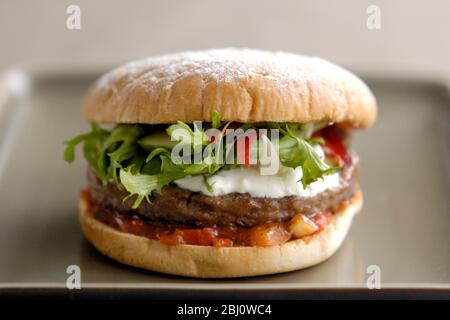 Hamburger vom Grill im Brötchen mit Friseuesalat, Gurke, Pfefferstreifen, Sauerrahm und Tomatensalsa - Stockfoto