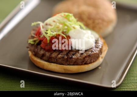 Hamburger vom Grill im Brötchen mit Friseuesalat, Tomatensalsa und saurer Sahne - - Stockfoto