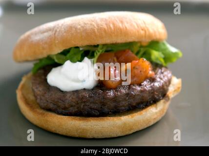 Hamburger vom Grill im Brötchen mit Friseuesalat, Tomatensalsa und saurer Sahne - Stockfoto
