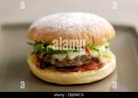 Hamburger vom Grill im Brötchen mit Friseuesalat, Gurke, Pfefferstreifen, geschmolzenem Käse, gegrilltem Speck und Tomatensalsa - Stockfoto