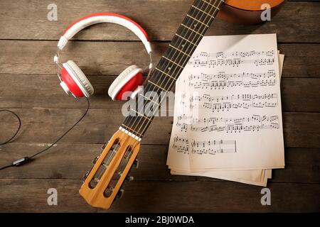 Musikaufnahme Szene mit Gitarre, Notenblätter und Kopfhörer auf Holztisch, Nahaufnahme Stockfoto