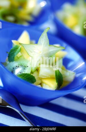 Frischer Obstsalat mit Sternfrucht und Kiwis in blauer Schüssel - Stockfoto