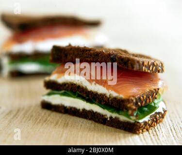 Geräuchertes Lachs- und Frischkäse-Sandwich auf dunklem Roggenbrot - Stockfoto