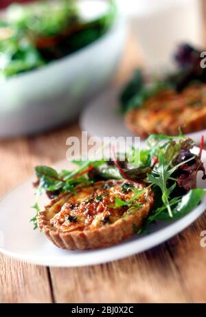 Tomaten und Käse Quiche serviert mit gemischten Blattsalat auf weißem Teller - Stockfoto