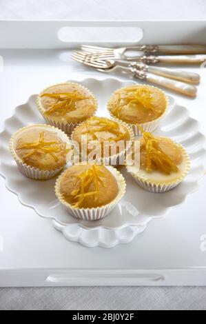 Zitronenmuffins mit Zitronenschale auf weißem Cakestand glasiert - Stockfoto