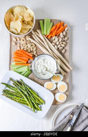 Hausgemachte Herby Schlagfahne Feta Dip auf einem Aperitif-Platte mit Chips, rohes Gemüse, Nüsse, Grillstäbchen, Spargel und gekochten Eiern Stockfoto