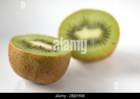 Kiwi-Frucht halbiert, um innere Textur und Struktur auf weißer Keramik-Oberfläche zu zeigen - Stockfoto