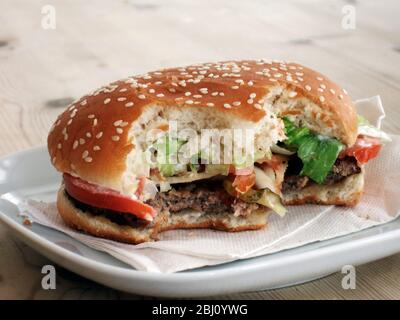 Hamburger gebissen auf weißem Teller - Stockfoto