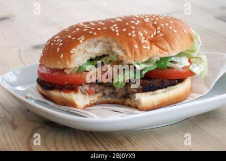 Hamburger gebissen auf weißem Teller - Stockfoto