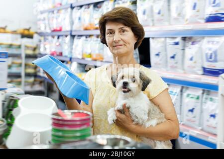 Frau besucht Tierhandlung auf der Suche nach Hund Schüssel für die Fütterung ihrer niedlichen havanese Stockfoto