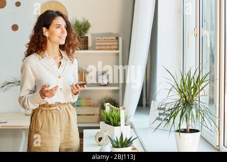 Schicke Managerin, die ihren Kollegen während eines Online-Meetings über das Smartphone etwas erzählt Stockfoto