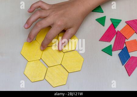 Tangram Hexagon Blume gefärbte Kind geometrische Puzzle Stück mit Hand Füllung in das letzte Stück auf braunem Hintergrund. Stockfoto