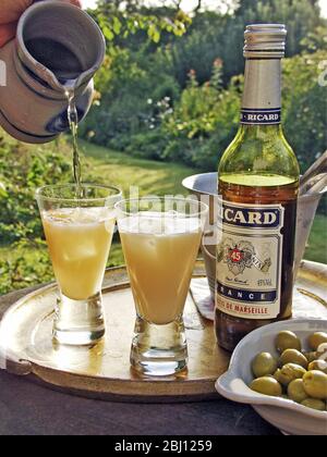 Zwei Gläser pernod-Getränk, das in der Abendsonne gegossen wird - Stockfoto