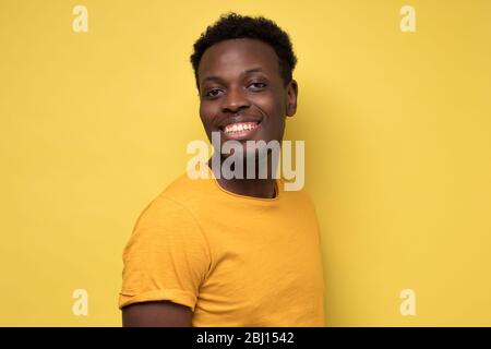 Junger afrikanischer Mann posiert vor der Kamera auf gelbem Hintergrund. Stockfoto