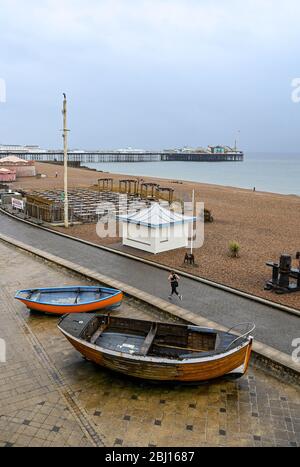 Brighton UK 28. April 2020 - EIN Läufer hat viel Platz entlang der Küste von Brighton, da kaltes nasses Wetter in Großbritannien nach wochenlanger Sonnenschein während der Sperrbeschränkungen angekommen ist, während die Pandemie-Krise des Coronavirus COVID-19 weiter andauert. Quelle: Simon Dack / Alamy Live News Stockfoto