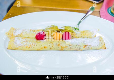 Crepes gefüllt mit Schokolade und Beeren mit Walderdbeeren und Umhang Stachelbeeren Stockfoto