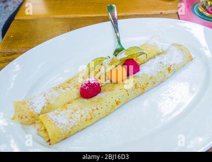 Crepes gefüllt mit Schokolade und Beeren mit Walderdbeeren und Umhang Stachelbeeren Stockfoto