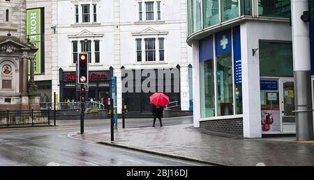 Brighton UK 28. April 2020 - Regenschirme sind auf den ruhigen Straßen von Brighton, da kaltes nasses Wetter in Großbritannien nach wochenlangen Sonnenstrahlen während der Sperrbeschränkungen angekommen ist, während die Pandemie-Krise des Coronavirus COVID-19 weiter andauert. Quelle: Simon Dack / Alamy Live News Stockfoto