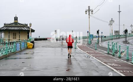 Brighton UK 28. April 2020 - EINIGE Läufer haben viel Platz entlang der Küste von Brighton, da kaltes nasses Wetter nach wochenlangem Sonnenschein während der Sperrbeschränkungen in Großbritannien angekommen ist, während die Pandemie-Krise des Coronavirus COVID-19 andauert. Quelle: Simon Dack / Alamy Live News Stockfoto