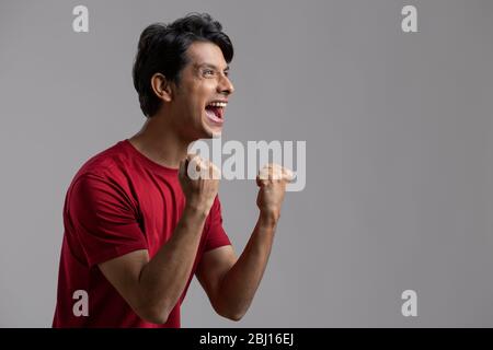 Junger Mann, der voller Aufregung und Jubel die Faust zusammenklammerte Stockfoto