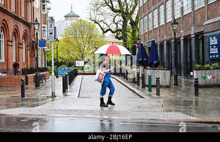 Brighton UK 28. April 2020 - Regenschirme sind auf den ruhigen Straßen von Brighton, da kaltes nasses Wetter in Großbritannien nach wochenlangen Sonnenstrahlen während der Sperrbeschränkungen angekommen ist, während die Pandemie-Krise des Coronavirus COVID-19 weiter andauert. Quelle: Simon Dack / Alamy Live News Stockfoto