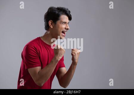 Junger Mann, der voller Aufregung und Jubel die Faust zusammenklammerte Stockfoto