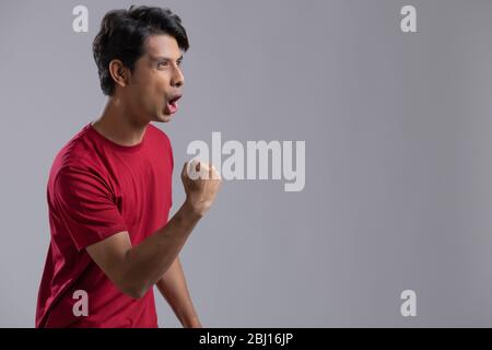 Junger Mann, der voller Aufregung und Jubel die Faust zusammenklammerte Stockfoto