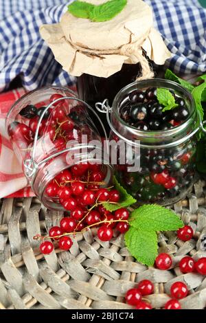 Reife Waldbeeren im Glasgefäß und leckere Marmelade auf Holzhintergrund Stockfoto