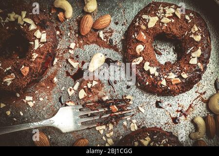 Köstliche Donuts mit Schokolade Glasur und Nüsse auf dem Tisch aus nächster Nähe Stockfoto