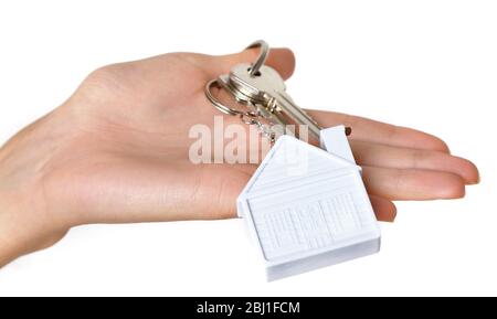 Weibliche Hand Schlüssel mit Haus Schlüsselanhänger auf weißem Backstein Wand Hintergrund Stockfoto